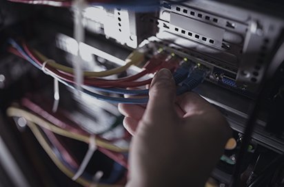 Engineer connecting cabling in a production network rack